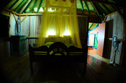 a bedroom with a bed with a yellow curtain at 4 Pohon - Les 4 Arbres in Pandang