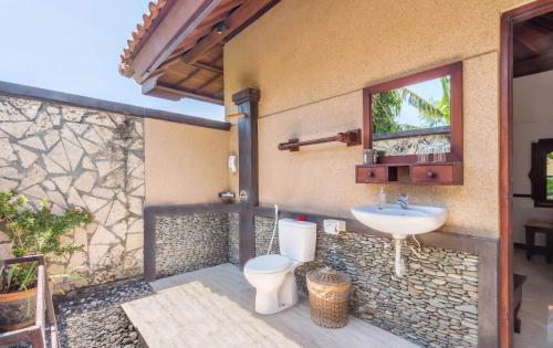 a bathroom with a toilet and a sink at Adi Assri Beach Resorts And Spa Pemuteran in Pemuteran