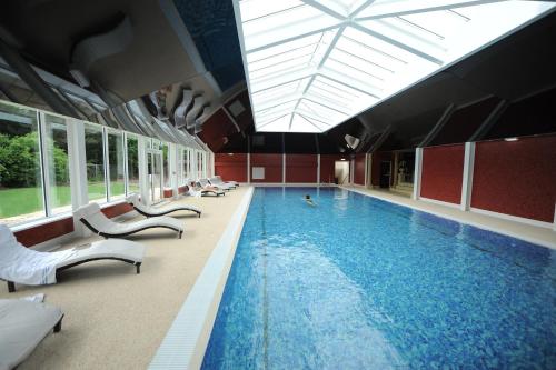 a large swimming pool with white chairs and a large pool at The Parsonage Hotel & Spa in Escrick