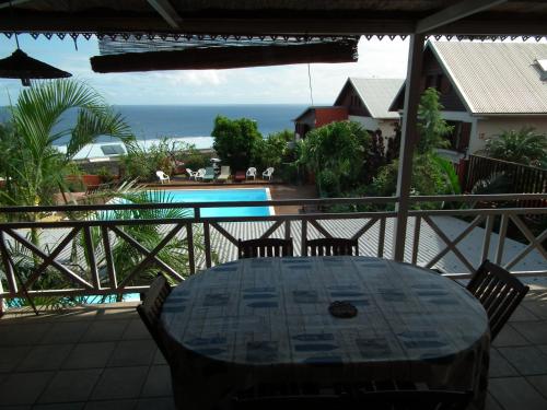 a table on a balcony with a view of the ocean at Le Cardinal des Grands Bleus in Saint-Leu