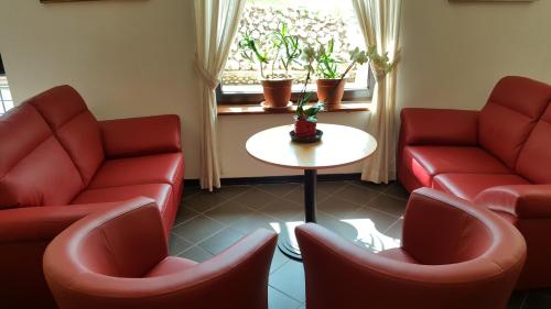 a waiting room with red chairs and a table at Hotel del Lago Ampollino in Torre Caprara