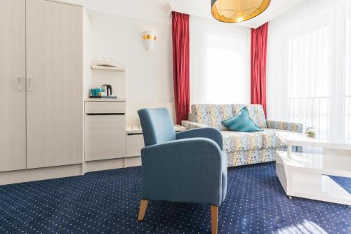 ein Wohnzimmer mit einem blauen Stuhl und einem Sofa in der Unterkunft Haffidyll garni in Rerik