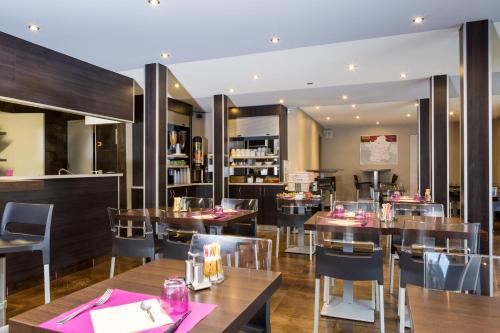 a restaurant with wooden tables and chairs and a restaurant with pink napkins at Initial by balladins Lyon / Chanas in Chanas