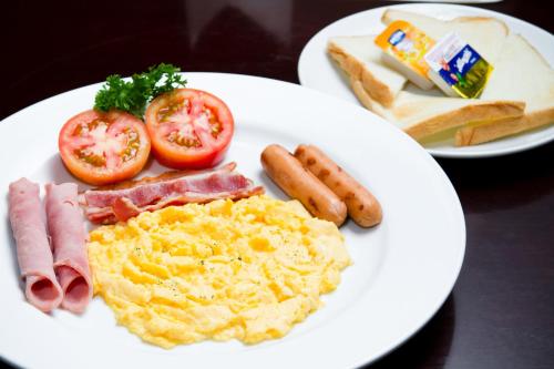 a plate of breakfast food with eggs bacon tomatoes and bread at Vabua Asotel Bangkok in Bangkok
