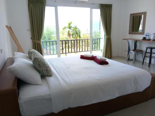 a bedroom with a large white bed with a balcony at The Wang in Chalong