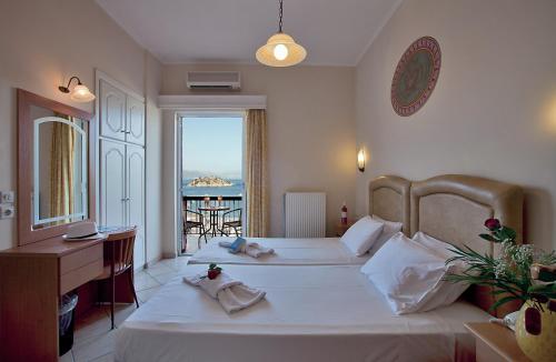 a bedroom with two beds and a desk and a balcony at Epidavria Hotel in Tolo