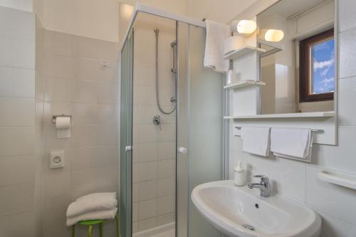 a white bathroom with a shower and a sink at Hotel Cecile in Pisa