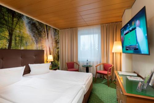 a hotel room with a bed and a flat screen tv at AHORN Waldhotel Altenberg in Kurort Altenberg