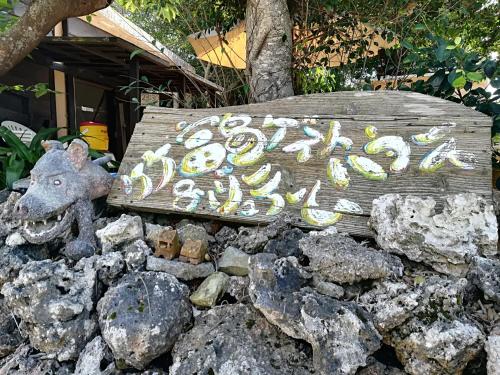 a sign sitting on top of a pile of rocks at Taketomijima Guesthouse and je Taime in Taketomi
