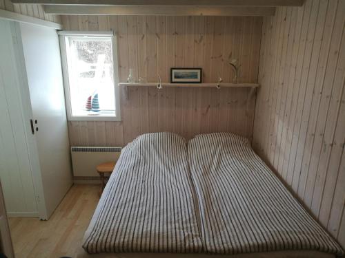 ein gestreiftes Bett in einem Zimmer mit Fenster in der Unterkunft Åsarna Hills Holiday Home Stillingsön in Stillingsön