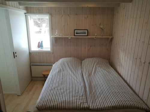 a striped bed in a room with a window at Åsarna Hills Holiday Home Stillingsön in Stillingsön