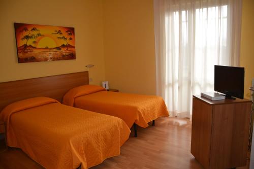 a hotel room with two beds and a flat screen tv at Piccolo Hotel in Rosignano Solvay