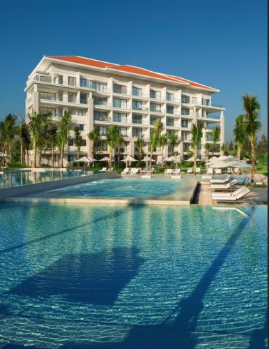 a hotel with a swimming pool in front of a building at Sunshine Apartment in 5* resort in Da Nang