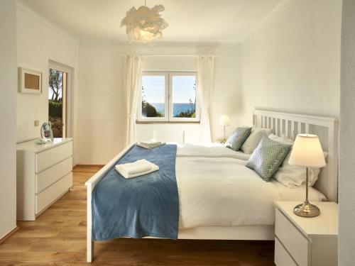 1 dormitorio con 1 cama blanca grande con manta azul en E&M Beach House Aldeamento do Levante I, en Armação de Pêra