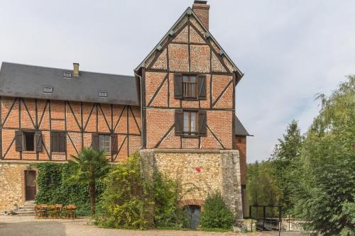 un grande edificio in mattoni con tetto nero di Le moulin de la côte chambre d'hôtes a Saint-Vigor