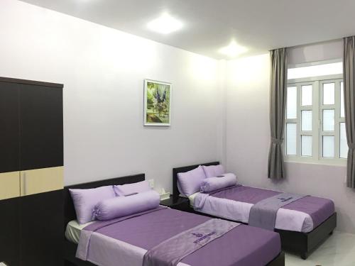 two beds in a room with purple pillows at HT Hotel Apartment in Ho Chi Minh City