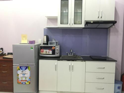 a kitchen with white cabinets and a refrigerator at HT Hotel Apartment in Ho Chi Minh City