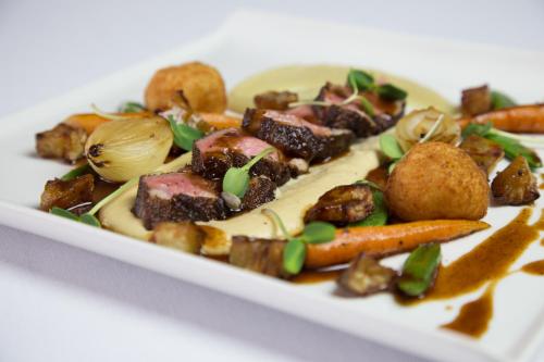 a white plate of food with meat and vegetables at Lairds Lodge Country Estate in Plettenberg Bay