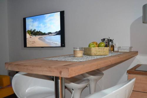 a kitchen with a table with a tv on the wall at Studio M in Mindelo