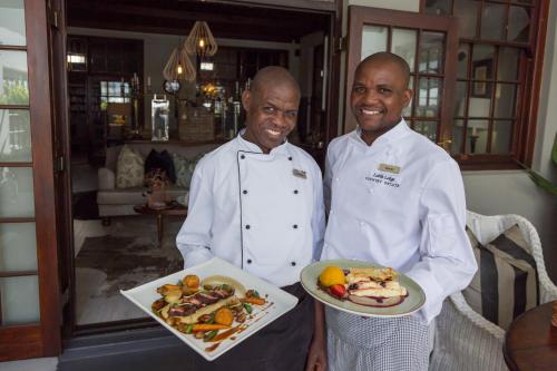 two men are standing next to each other holding food at Lairds Lodge Country Estate in Plettenberg Bay