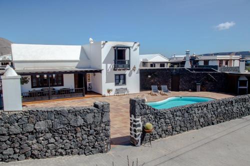 a house with a stone wall and a swimming pool at casa los veroles lanzarote in El Islote