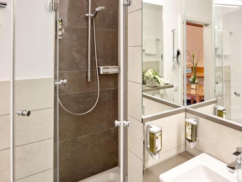 uma casa de banho com um chuveiro e um lavatório. em Hotel Fürstenhof - Wellness- und Golfhotel em Bad Griesbach