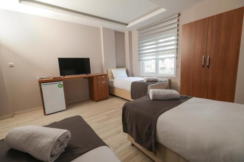 a hotel room with two beds and a television at Grand Dost Hotel in Osmancık