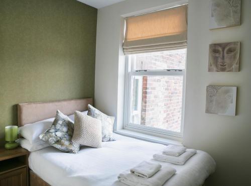 a bedroom with a bed and a window with towels on it at The Green House classic 2 bedroom apartment in Harrogate