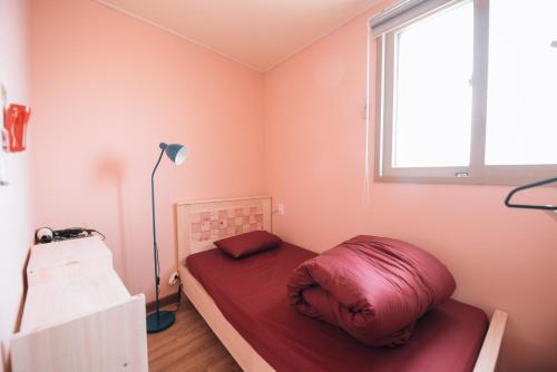 a small bedroom with a bed with a red pillow at Daegu Midtown Hostel in Daegu