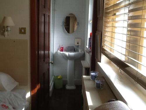 een badkamer met een witte wastafel en een spiegel bij Arron House in Hamilton
