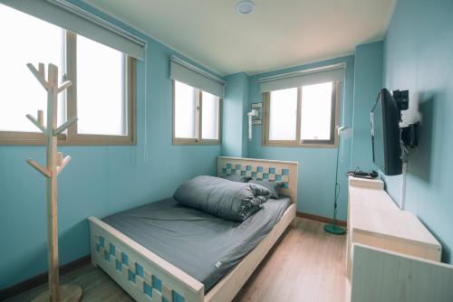 a bedroom with blue walls and a bed and a tree at Daegu Midtown Hostel in Daegu