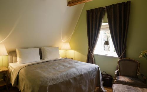 a bedroom with a bed and a chair and a window at Kokkedal Slot Copenhagen in Hørsholm