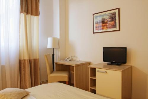 una camera d'albergo con letto e scrivania con TV di Garni Hotel Hamburg a Zaječar