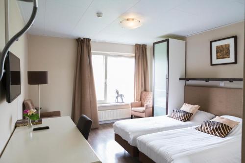 Cette chambre comprend 2 lits et une table. dans l'établissement Human & Horse Hotel, à Kootwijkerbroek