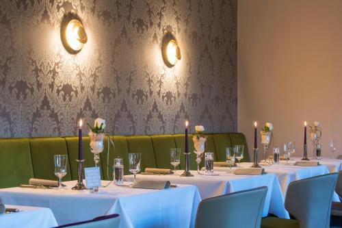 a row of tables with white table cloths and candles at IDINGSHOF Hotel & Restaurant in Bramsche