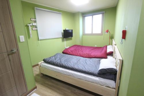 a bed in a room with green walls and a window at Daegu Midtown Hostel in Daegu