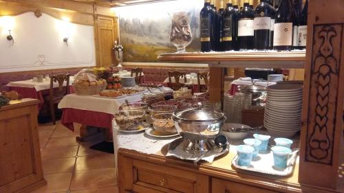 a kitchen with a table with food and bottles of wine at Hotel Alpina in Pinzolo