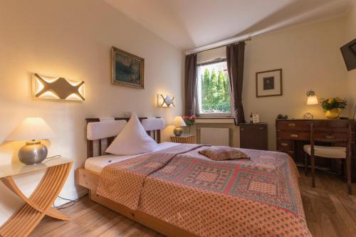 Schlafzimmer mit einem Bett, einem Schreibtisch und einem Fenster in der Unterkunft Hotel Villa Meererbusch in Meerbusch