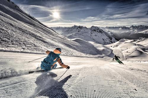 two people are skiing down a snow covered mountain at Sporthotel Silvretta Montafon in Gaschurn