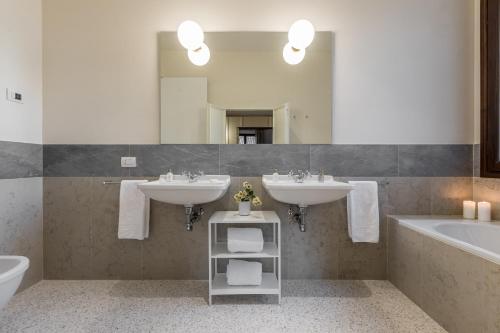 ein Badezimmer mit zwei Waschbecken, einer Badewanne und einem Spiegel in der Unterkunft Sartor Apartment with Canal View and Private Court in Venedig