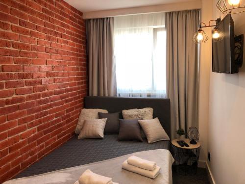 a room with a brick wall and a bed with pillows at Family & Business Sauna Apartments Rynek Centrum Downtown - 2 Bedroom with Private Sauna, Balcony, Parking in Kielce