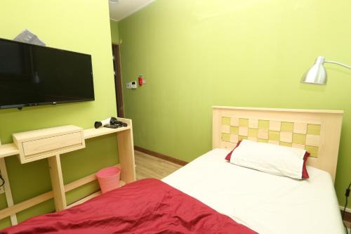 a bedroom with a bed and a flat screen tv at Daegu Midtown Hostel in Daegu