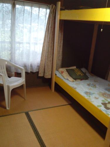 um beliche para crianças com uma cadeira e uma janela em raibrasil guest house em Sanuki