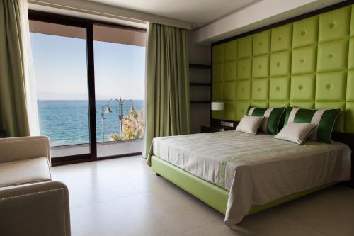 a bedroom with a large bed with a view of the ocean at Ngonia Bay Boutique Hotel in Milazzo