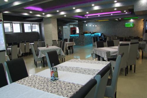 una sala da pranzo con tavoli, sedie e luci viola di B&B Hisar International a Prijepolje