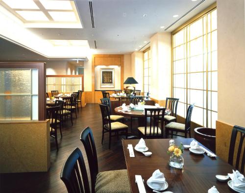 a dining room with tables and chairs and windows at JR Hotel Clement Takamatsu in Takamatsu
