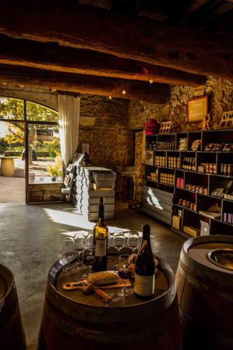 - une cave à vin avec des bouteilles de vin et des verres sur un tonneau dans l'établissement Mas du Notaire, à Gallician