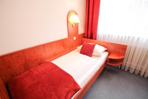 a bed in a room with a red blanket at Hotel West an der Bockenheimer Warte in Frankfurt/Main