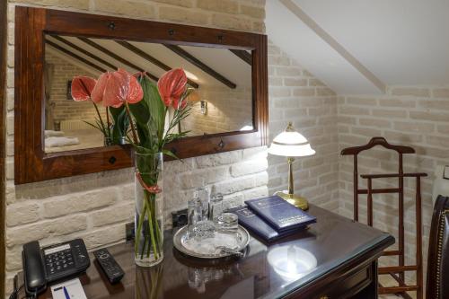a desk with a vase of flowers and a phone at La Gioconda Boutique Hotel in Odesa