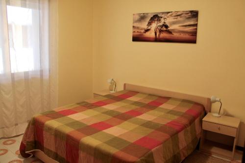 a bedroom with a bed with a plaid blanket and a window at Claudia 3 in Grado
